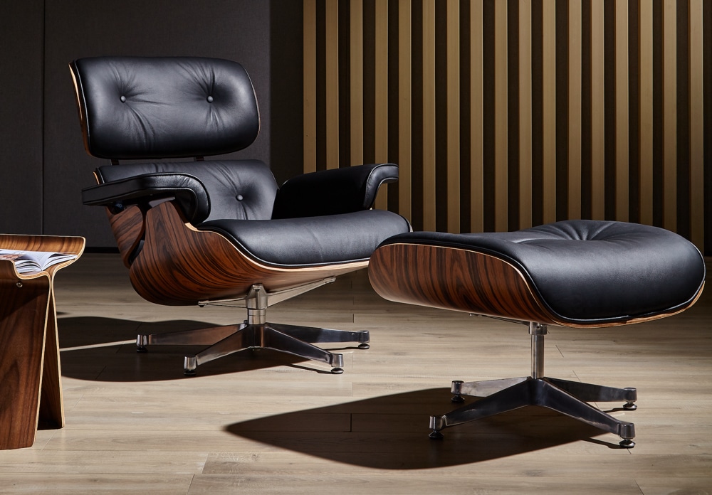 fauteuil charles eames avec ottoman cuir italien noir bois de palissandre base en aluminium chromé poli dans un salon lounge